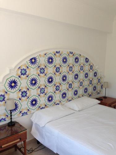 a white bed with a blue and white patterned headboard at Hotel 4 Stagioni in Capri