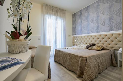 a bedroom with a bed and a table and a vase of flowers at Hotel Athena in Cervia