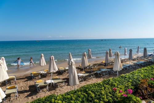 a beach with chairs and umbrellas and the ocean at Talgo Suites in Stalida