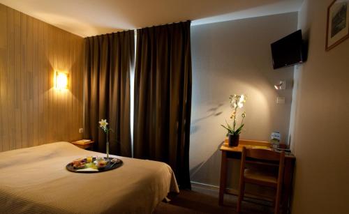 a hotel room with a bed with a tray of food on it at Logis Hôtel Le Relais in Biscarrosse