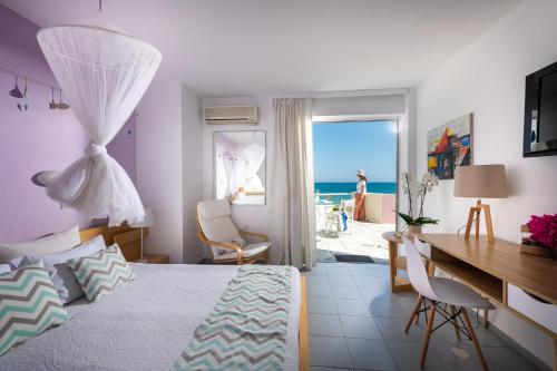 um quarto com uma cama e uma secretária e vista para o oceano em Talgo Suites em Stalida