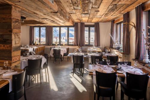 a restaurant with tables and chairs in a room with windows at Chalet Josianne in Saas-Fee