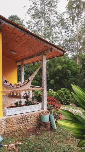 a wooden pavilion with a hammock in a garden at Pousada Polessas in Visconde De Maua