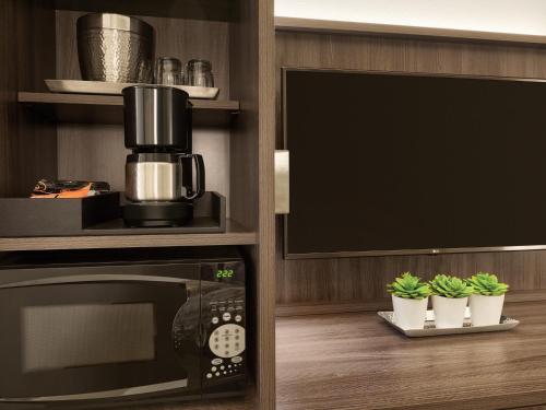 a kitchen with a microwave and a tv at Buena Vista Suites Orlando in Orlando