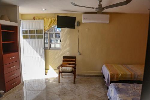 a bedroom with a bed and a chair and a tv at Casa Caridad del Cobre in Isla Mujeres