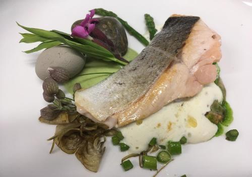a piece of meat on a white plate with vegetables at Bed&Bike Tremola San Gottardo in Airolo