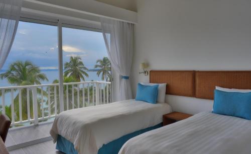 a hotel room with two beds and a balcony at BlueBay Vacation Rentals at Vista Mare in Santa Bárbara de Samaná