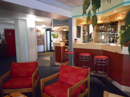a bar with red chairs and a counter in a restaurant at Hotel Inn Design Moutiers in Moutiers