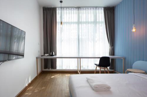 Un dormitorio con una cama y un escritorio y una ventana. en Boxpackers Hostel Phranakorn, en Bangkok