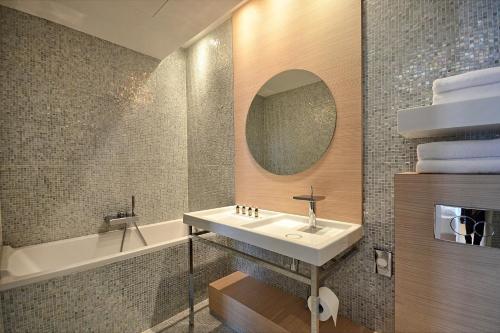 a bathroom with a sink and a tub and a mirror at Sound Garden Hotel Airport in Warsaw