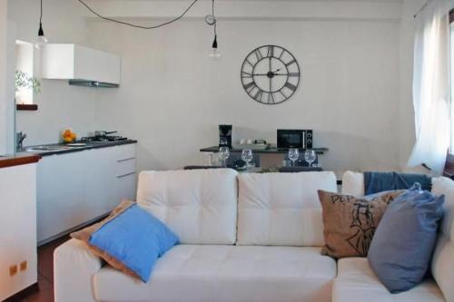 un divano bianco in soggiorno con un orologio sul muro di CASA MELL a Limone sul Garda