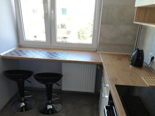a kitchen with two stools in front of a window at Apartament Nad Dziwną in Dziwnów