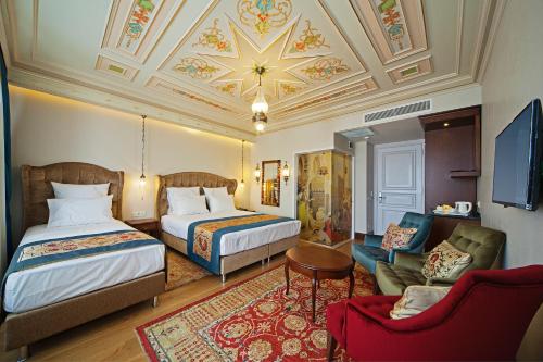 イスタンブールにあるAzade Premier Hotelのベッド2台とソファが備わるホテルルームです。