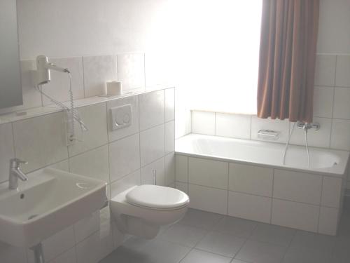 a white bathroom with a toilet and a sink at Hotel Zur Sonne in Kirchhain