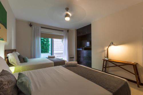 a hotel room with two beds and a window at Via Tendenza Condos in Playa del Carmen