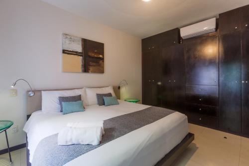 a bedroom with a large white bed with blue pillows at Via Tendenza Condos in Playa del Carmen