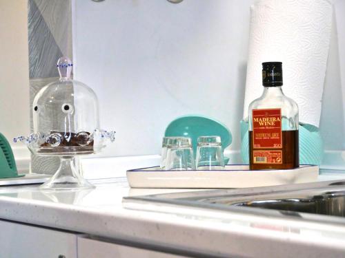 a bottle of whiskey and glasses on a kitchen counter at Casa do pescador in Machico