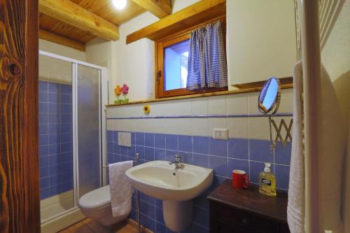 bagno piastrellato blu con lavandino e servizi igienici di Monolocale Gemma Locanda Codirosso a Stroppo