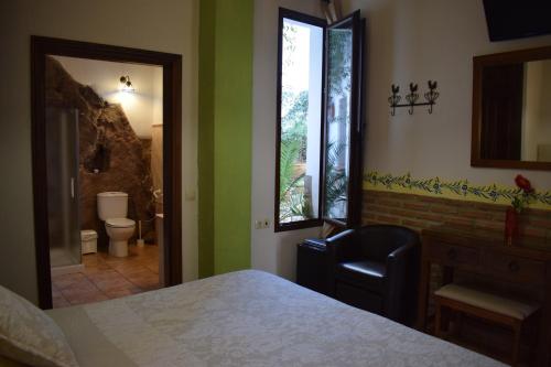ein Schlafzimmer mit einem Bett und einem Spiegel sowie ein Badezimmer in der Unterkunft Hostal Rural Molino Del Bombo in Aracena