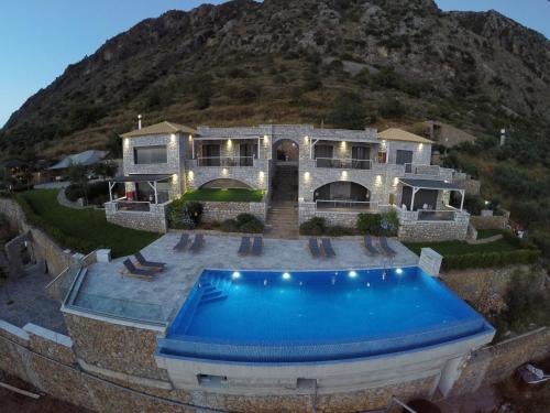 a house with a swimming pool in front of a mountain at Petra Thea in Kalamata