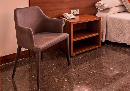 a chair and a phone next to a bed at Hotel Txartel in Lasarte