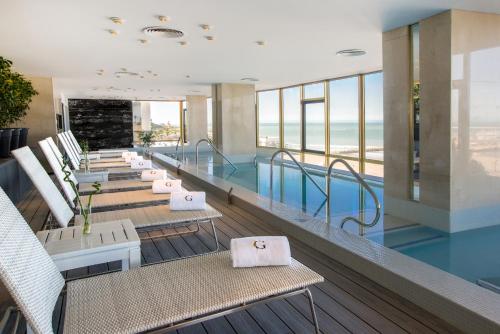 a hotel lobby with a swimming pool and chairs at Hotel Costa Galana in Mar del Plata
