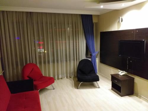 sala de estar con 2 sillas y TV de pantalla plana en Grand Ocakoğlu Hotel, en Izmir