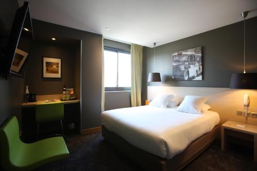 a hotel room with a bed and a green chair at Hotel De France in Valence