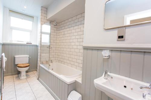 a bathroom with a tub and a toilet and a sink at The Queens Hotel in Lytham St Annes