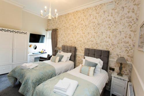two beds in a room with wallpaper at The Queens Hotel in Lytham St Annes