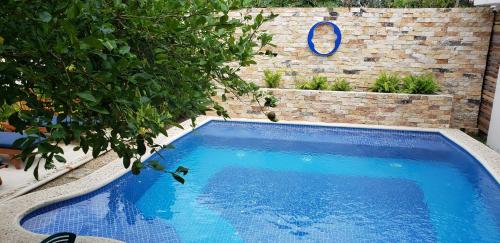 a large blue swimming pool next to a brick wall at Poza Clara Sanctuary in Bacalar