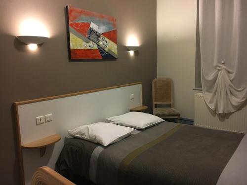 sypialnia z łóżkiem i obrazem na ścianie w obiekcie Hotel du Centre w mieście Gueugnon