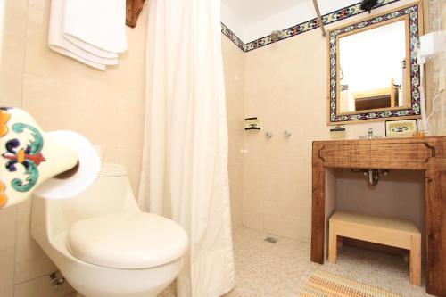 une salle de bains avec toilettes, lavabo et miroir dans l'établissement Hotel La Casa de Mamá, à San Cristóbal de Las Casas