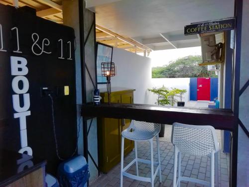 a bar with two white stools in a room at Studios 11and11Aruba in Palm-Eagle Beach
