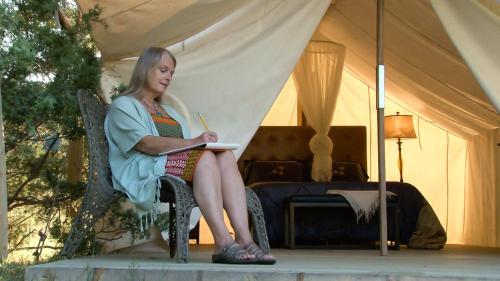 a woman sitting in a chair writing in a notebook at Allen Ranch in Hot Springs