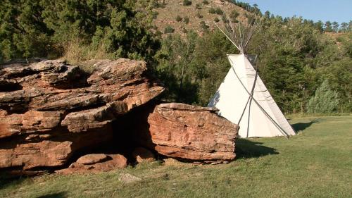 a white tent next to a rock in a field at Allen Ranch in Hot Springs