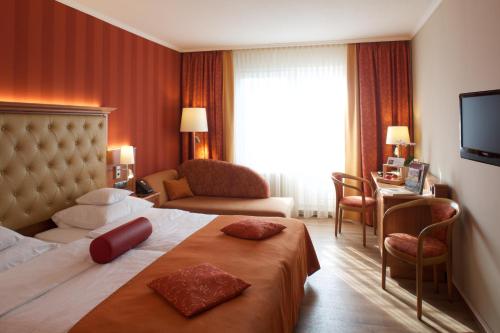 a hotel room with a bed and a couch and a television at Ringhotel Hotel Zum Stein in Oranienbaum-Wörlitz