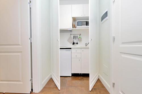 a white kitchen with white cabinets and a microwave at Piazza Venezia Grand Suite in Rome