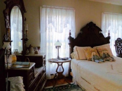 a bedroom with a bed and a table and windows at Belle Aire Mansion Guest House in Galena