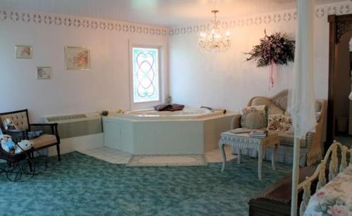 a bathroom with a tub and a table and a chair at Belle Aire Mansion Guest House in Galena