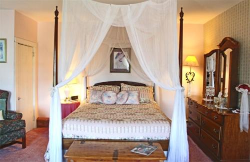 a bedroom with a canopy bed with twoeddy bears on it at Belle Aire Mansion Guest House in Galena
