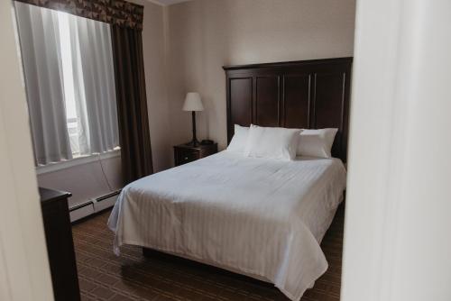 a bedroom with a large bed with white sheets and pillows at Prince Arthur Waterfront Hotel & Suites in Thunder Bay