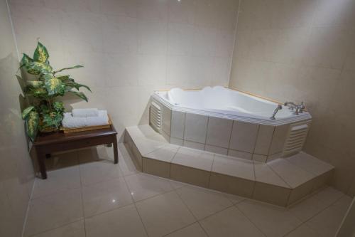a bath tub in a bathroom with a potted plant at Prince Arthur Waterfront Hotel & Suites in Thunder Bay
