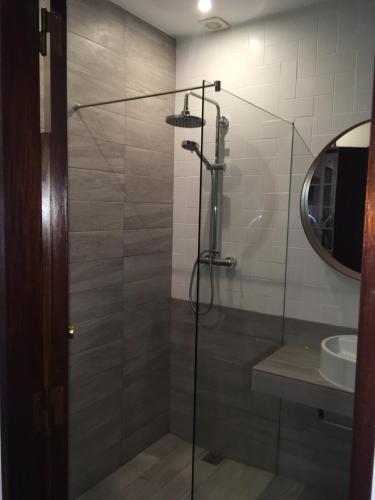 a shower with a glass door next to a sink at Apartamento Passarinhos in Albufeira