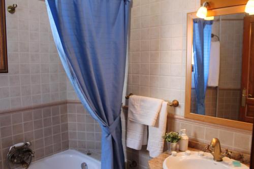 a bathroom with a blue shower curtain and a tub and sink at La Tila in Capileira