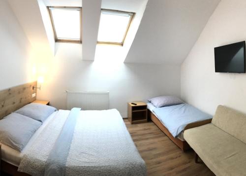 two beds in a room with a tv and a couch at Penzion Biely Potok in Terchová