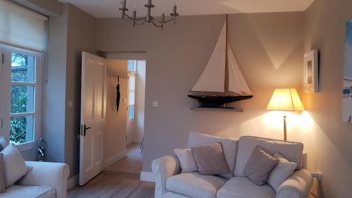a living room with a white couch and a boat on the wall at The Coach House Douglas in Cork