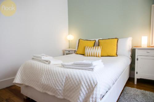 Una cama blanca con almohadas amarillas y toallas. en PAZ 38 - Premium Location en Lisboa