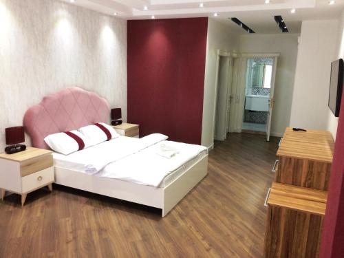 1 dormitorio con cama blanca y silla rosa en Park Azure Apartment Deluxe 2 Bedroom, en Baku