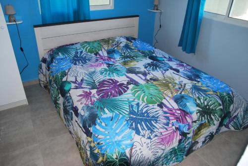Bett in einem blauen Zimmer mit Blumenbettdecke in der Unterkunft Villa Un Jour, Un Rêve in Chassaing